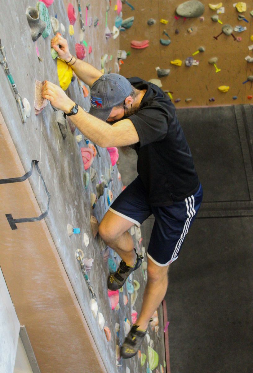 Walking by the rock wall in the UREC, a poster asking for shoes to be worn is posted, which leaves Andrew Weibers to tuff it out and put on shoes, at Whitworth University, Saturday, March. 5, 2022, in Spokane Wash.|Hannah Loesch/The Whitworthian"