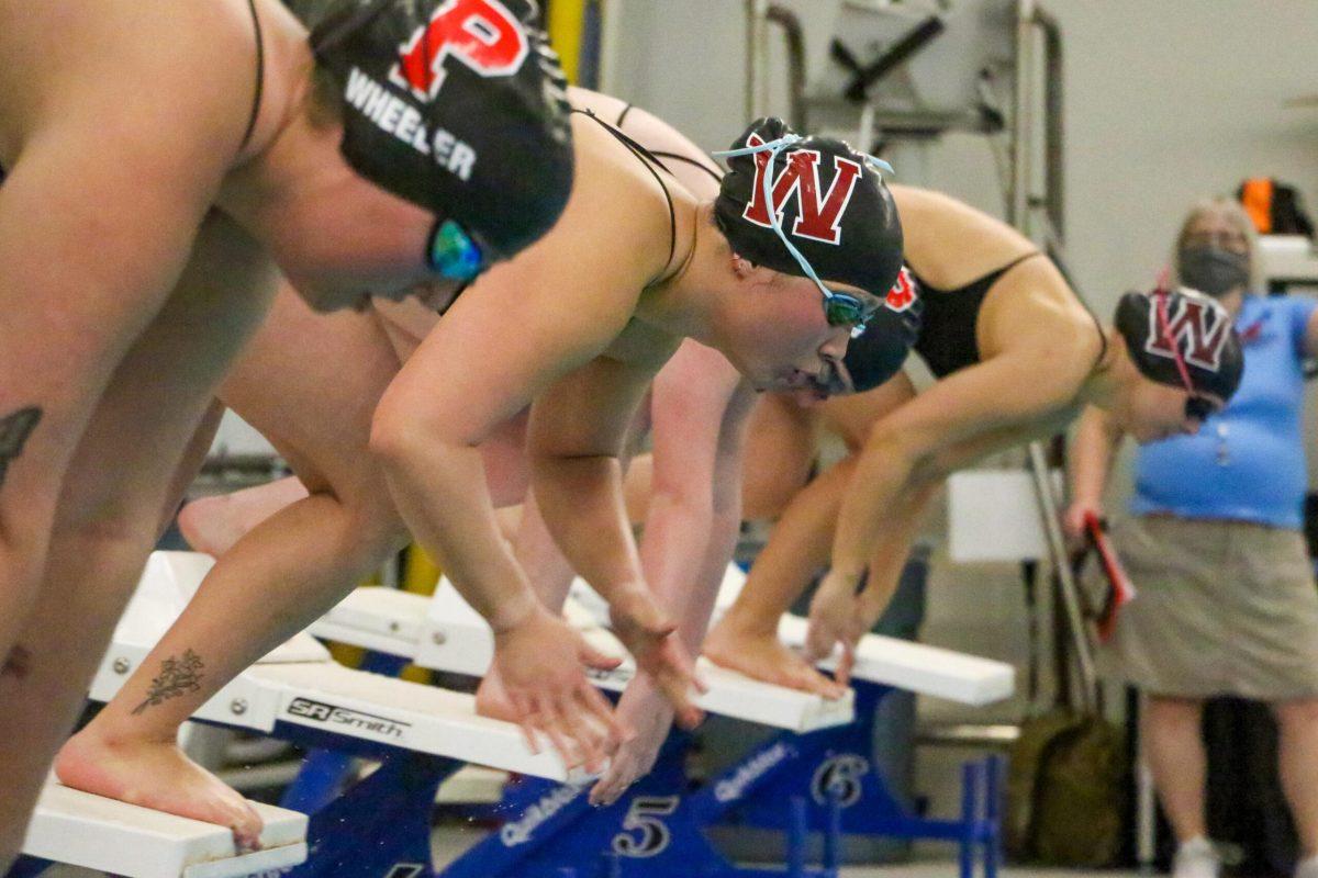 Jessica Defiesta (center) jumps off the starting blocks in the 100 yard freestyle during an NCAA college swimming meet at Whitworth University, Friday, Jan. 21, 2021, in Spokane, Wash. | Caleb Flegel/The Whitworthian