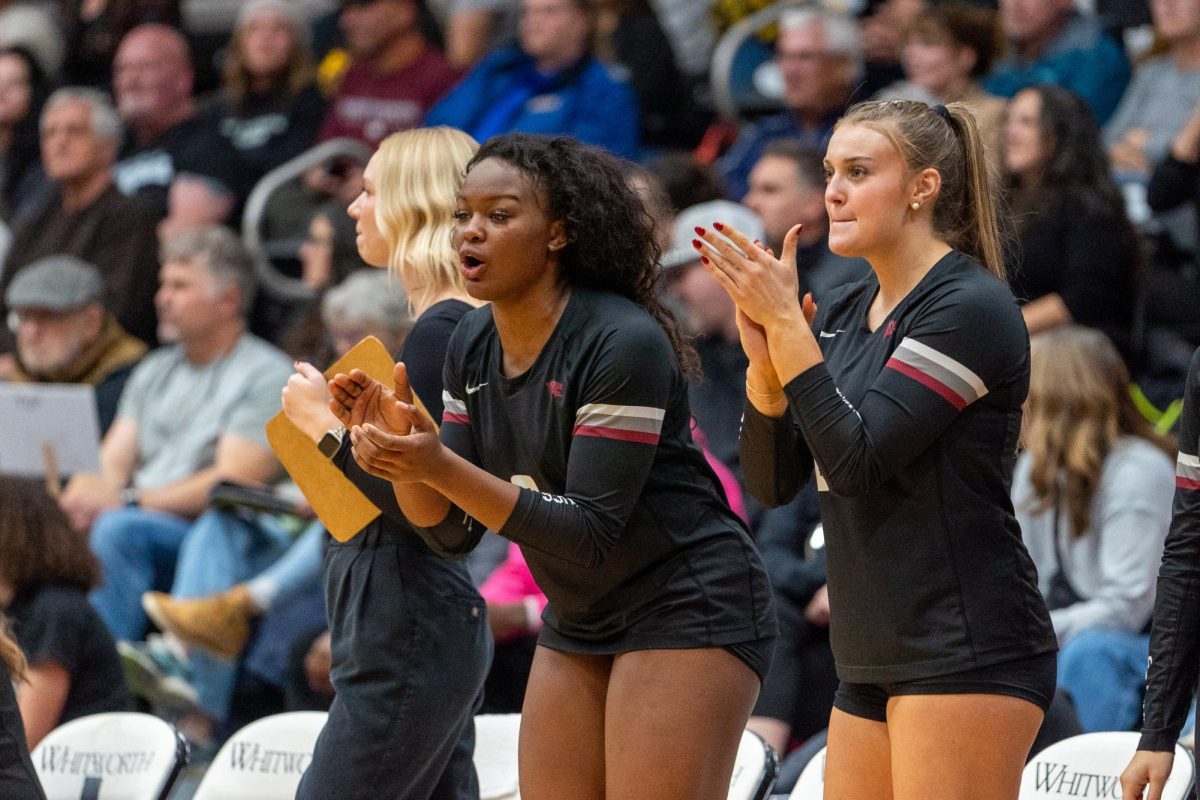 Amblessed Okemgbo (center) and Shelby Clixby (right) cheer on their team mates, Saturday, Nov. 9, 2024, at an NCAA volleyball game against Pacific Lutheran University at Whitworth University in Spokane, Wash. | Caleb Flegel/The Whitworthian