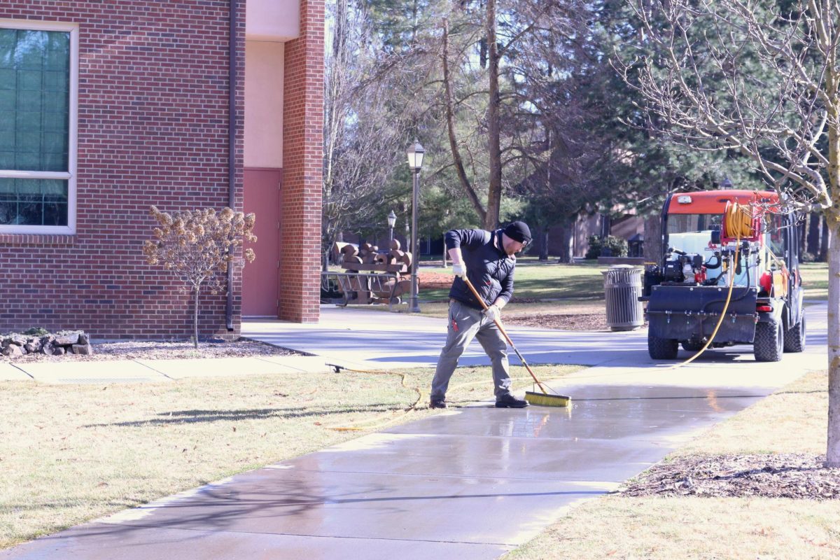 Facilities worker is photographed washing away chalk messages in the loop at Whitworth University, Wednesday, Feb. 11, 2026, in Spokane, Wash. | Jasmine Olson/The Whitworthian